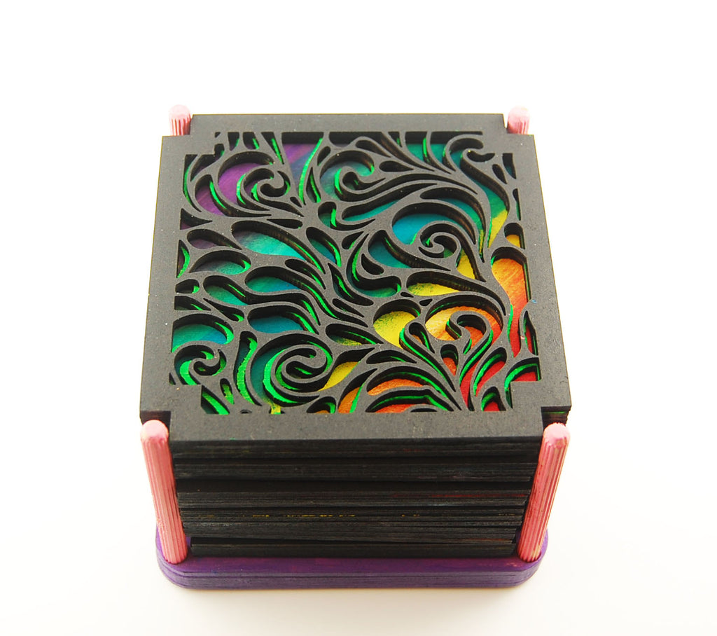 Six square laser-cut scrollwork coasters with colorful layered designs arranged together