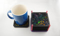 Colorful laser-cut scrollwork coaster set shown with a blue mug