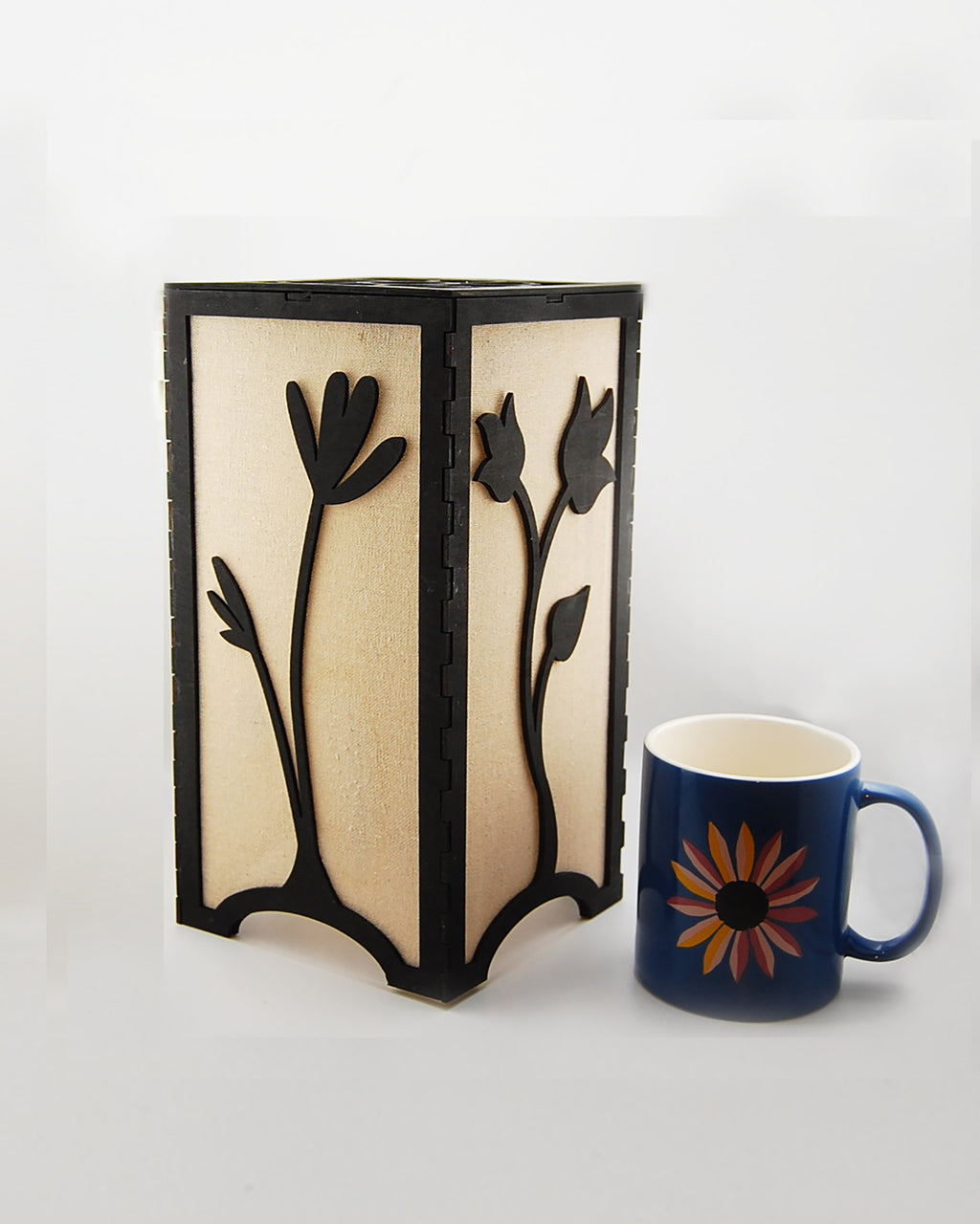 Floral tulip lantern unlit next to a coffee mug for scale