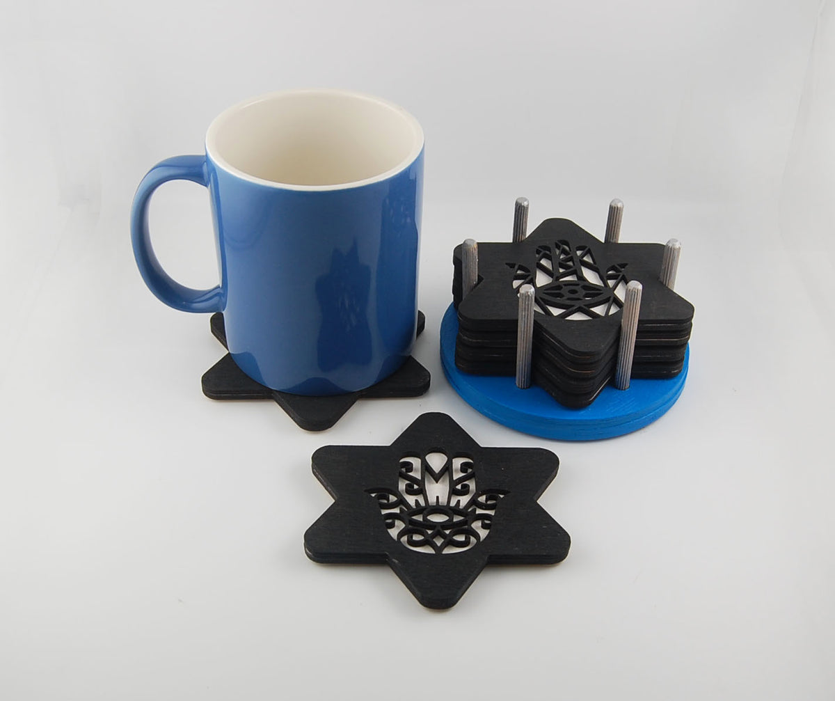Hamsa and Star of David Judaica coaster set shown beside a blue mug