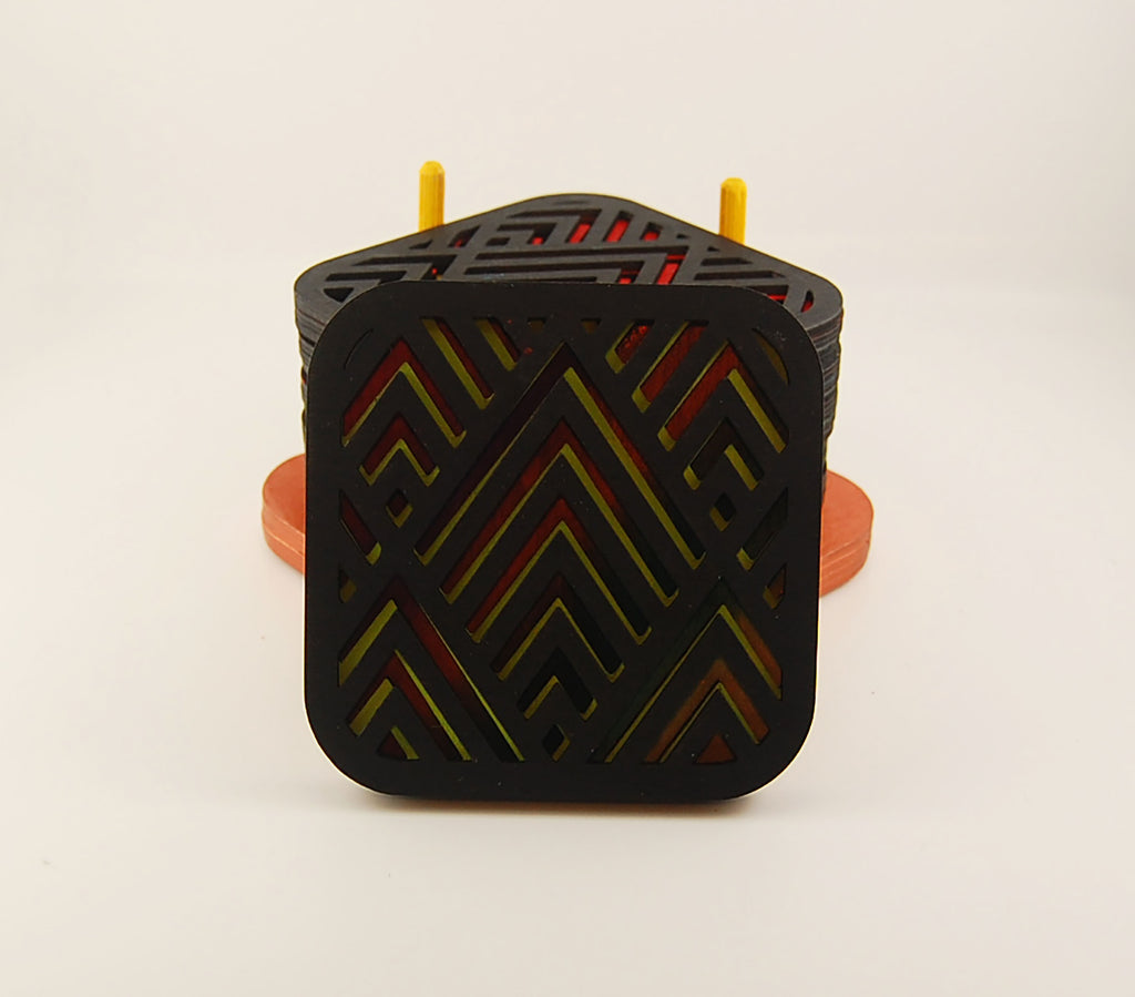 Square coaster with dark geometric angular pattern over a colorful design