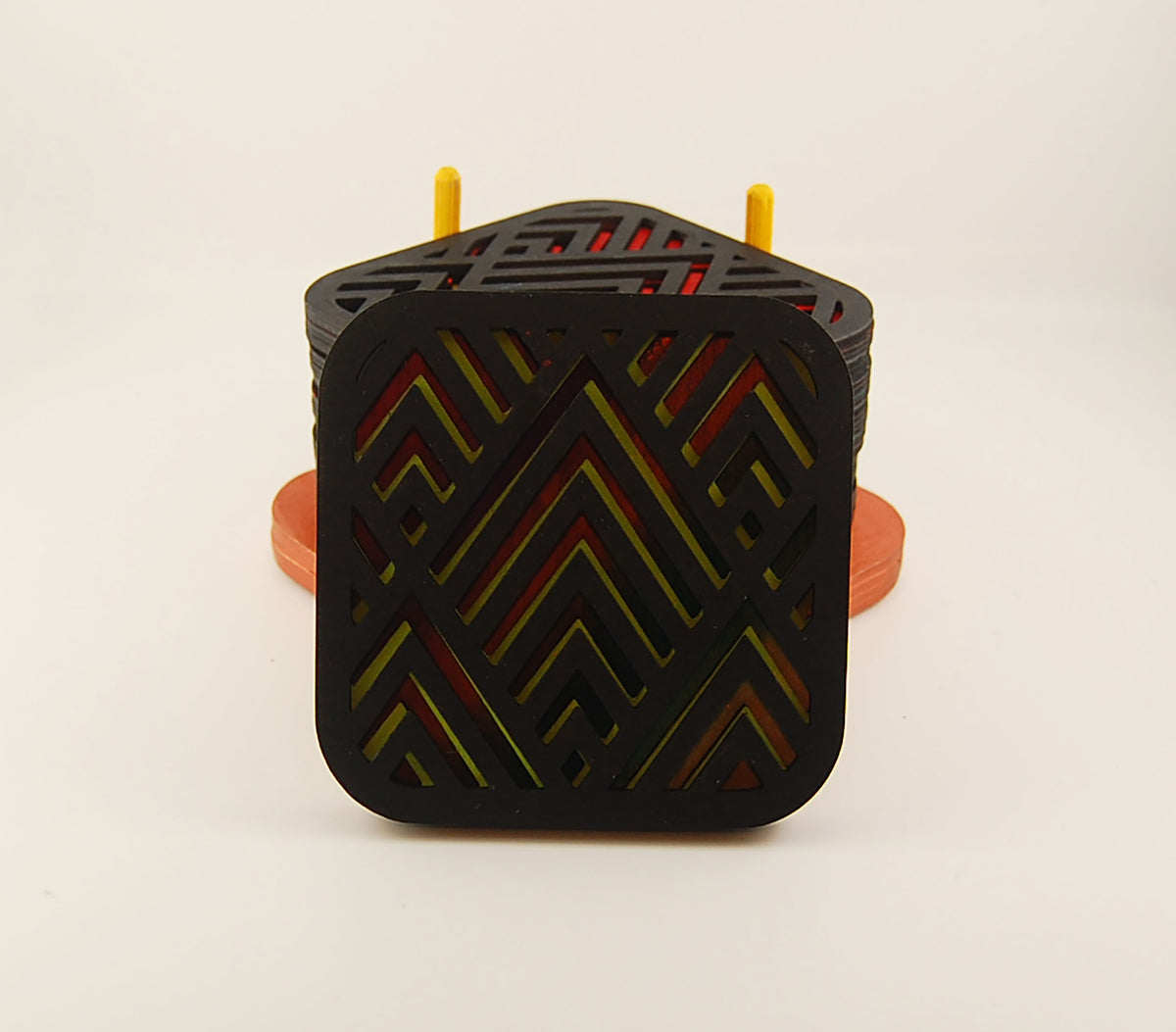 Square coaster with dark geometric angular pattern over a colorful design
