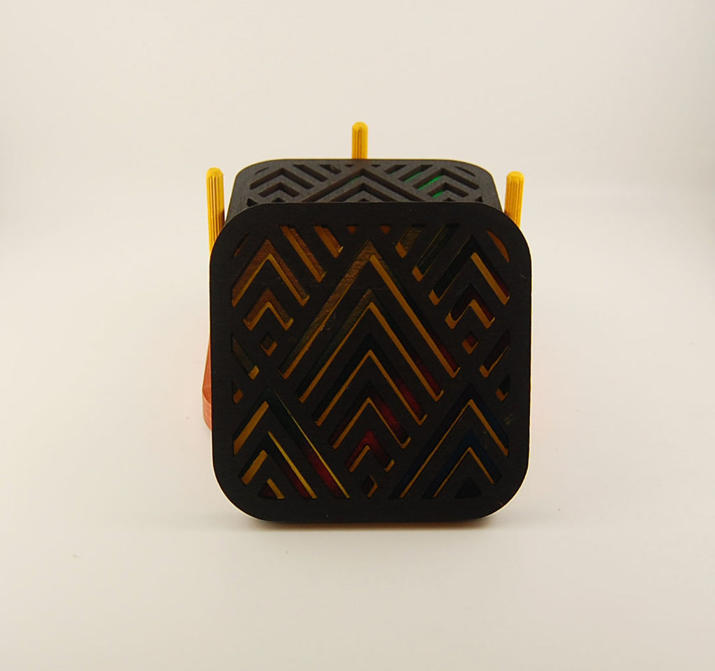 Square coaster showing layered colorful geometric pattern beneath a dark surface