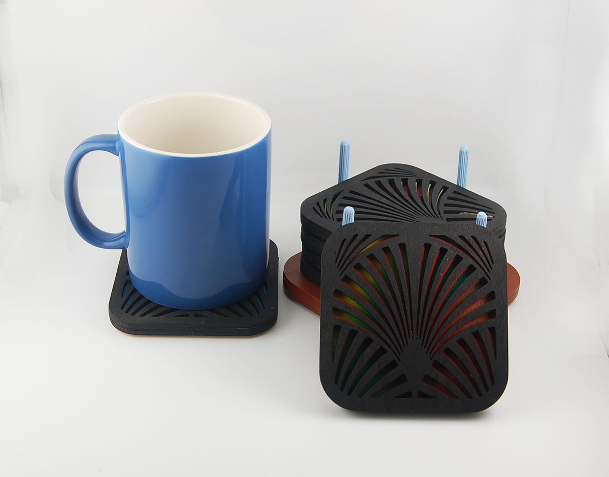 Square laser-cut Deco coaster set shown beside a blue mug