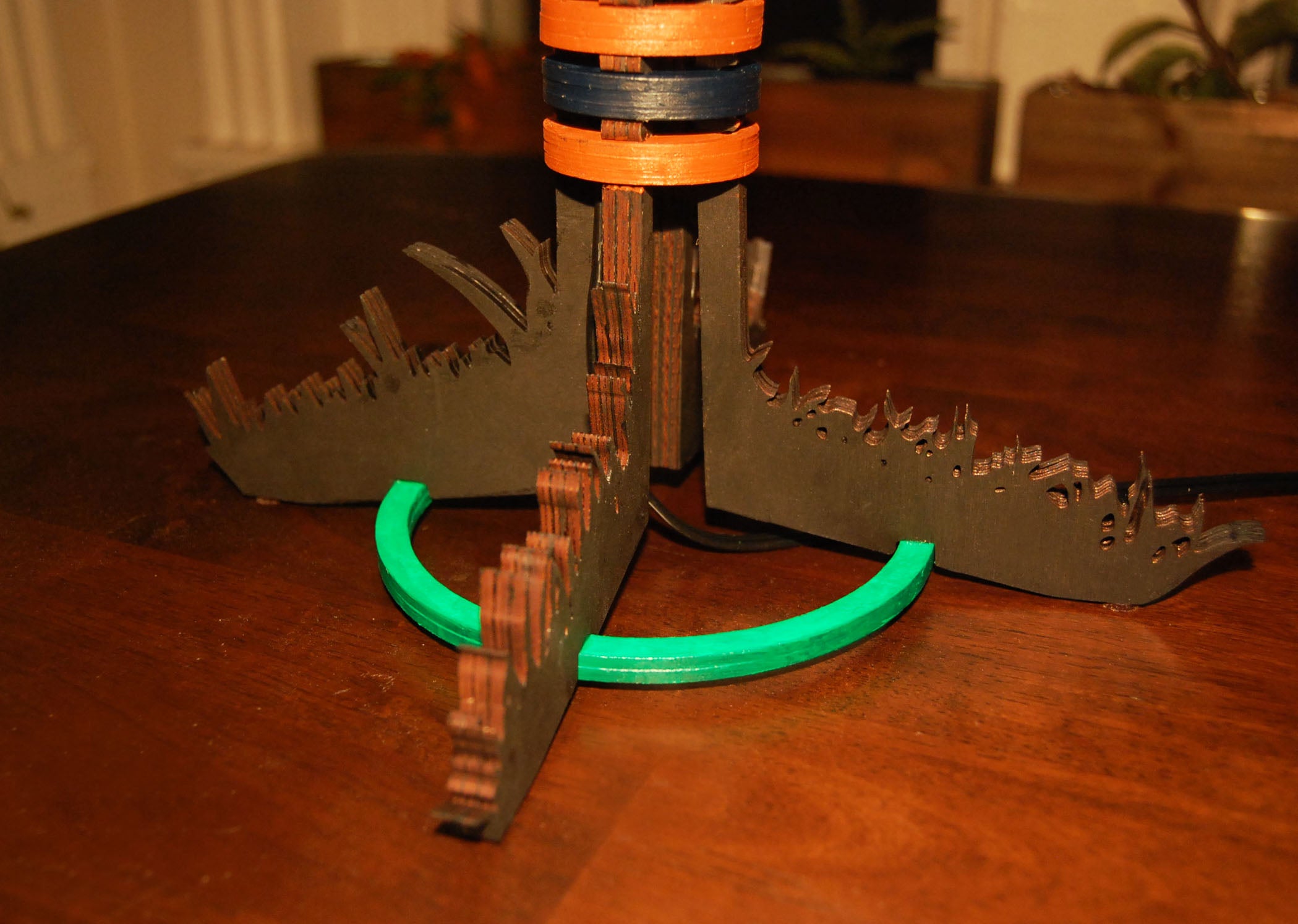 Base detail showing laser-cut grass silhouette and green painted basswood ring