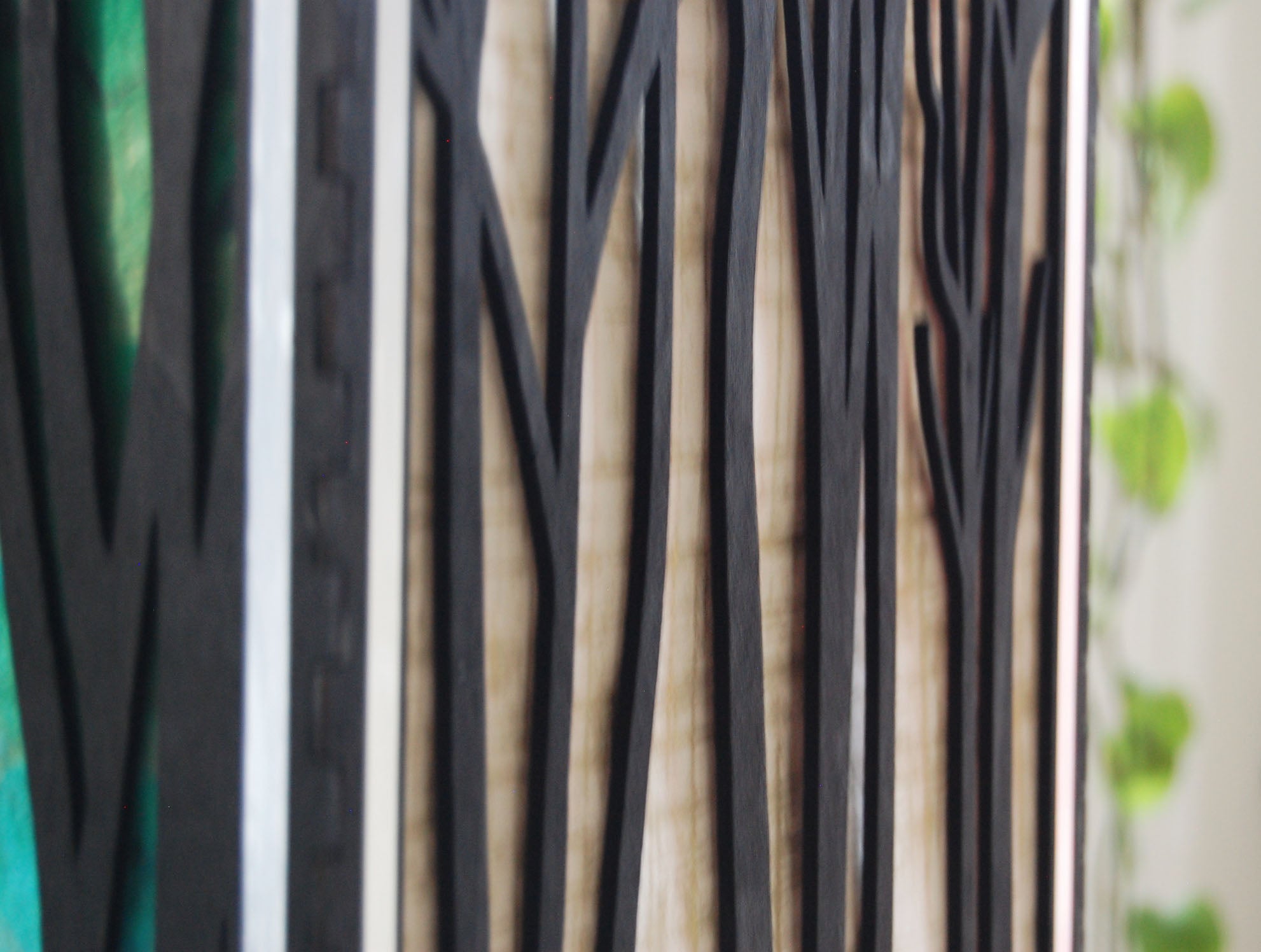 Close-up of natural basswood grain through laser-cut tree silhouette panel