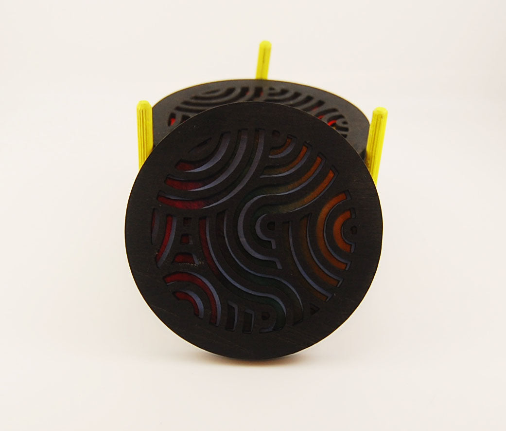 Round coaster showing colorful layered pattern beneath dark laser-cut waves