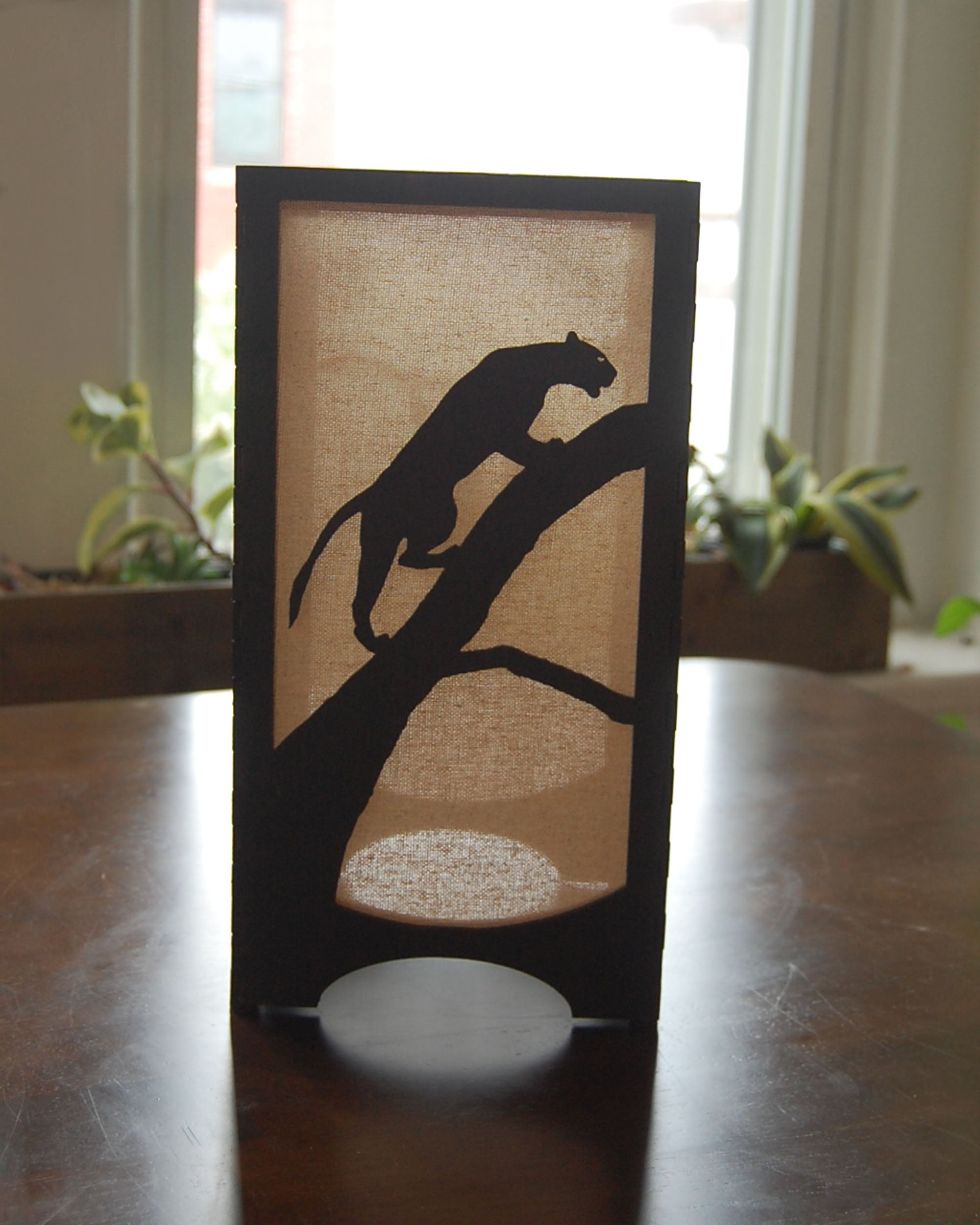 Handmade laser-cut wildlife lantern — panther silhouette  in natural light