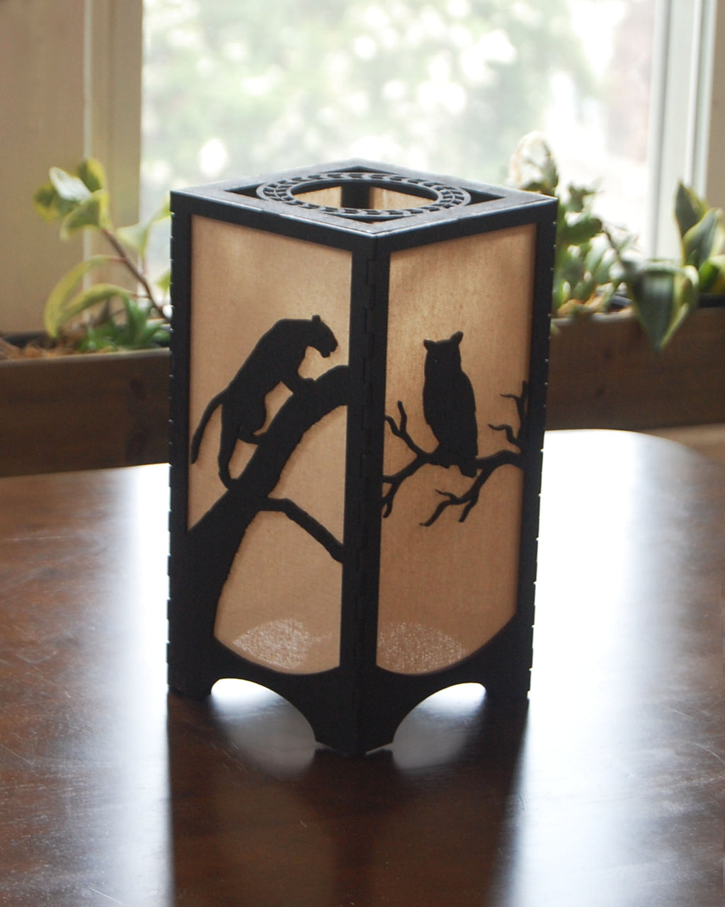 Handmade laser-cut wildlife lantern — panther and owl silhouettes  in natural light